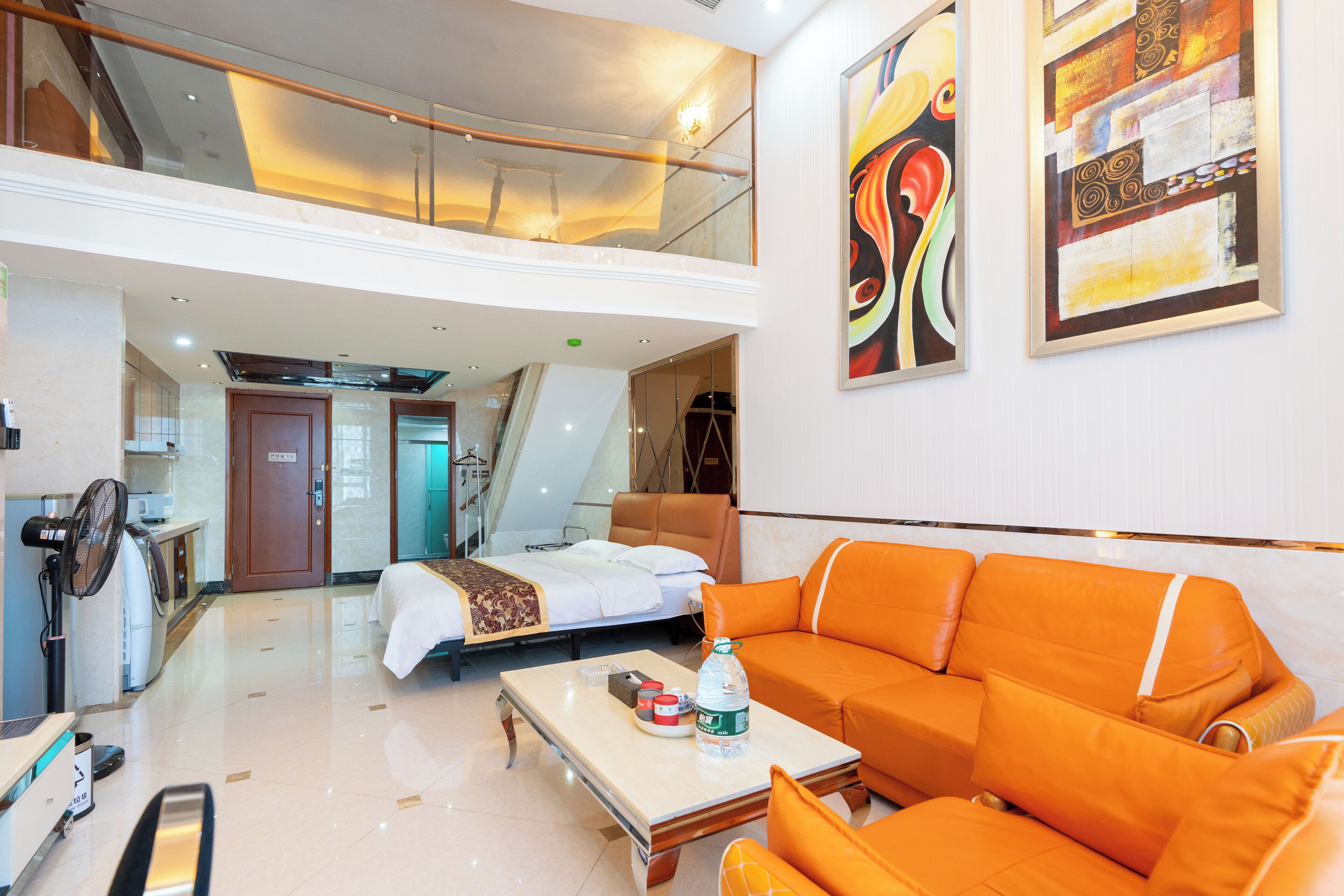 Een hotellobby met een bed, een oranje bank en kunstwerken aan de muren.