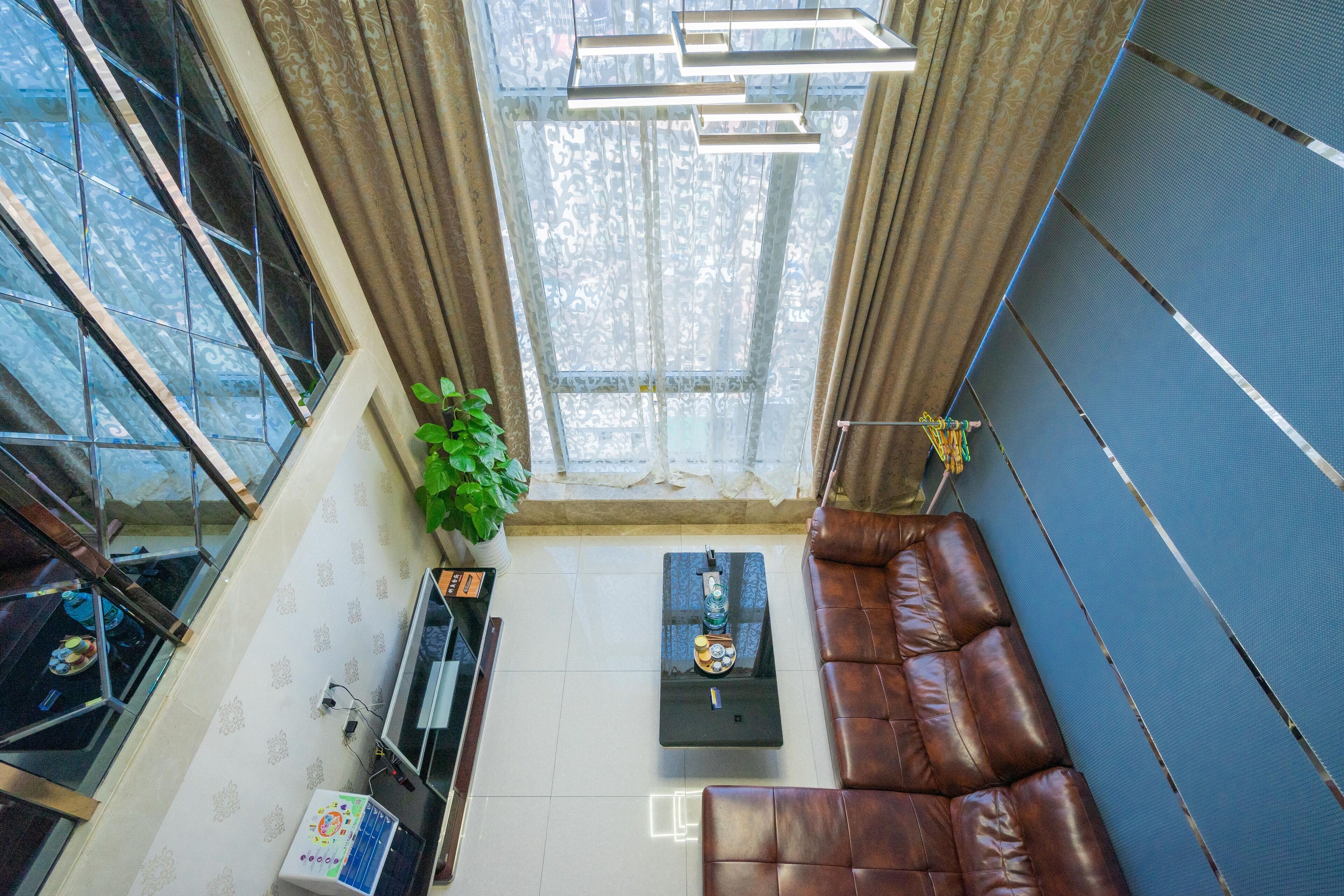 A modern living room with a brown leather sofa, a black coffee table, and a large window with curtains.