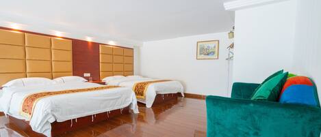 A hotel room with two beds, a green sofa, wooden flooring, and a painting on the wall.