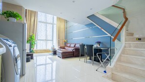 Una sala moderna con un sofá, una mesa de comedor y una escalera.