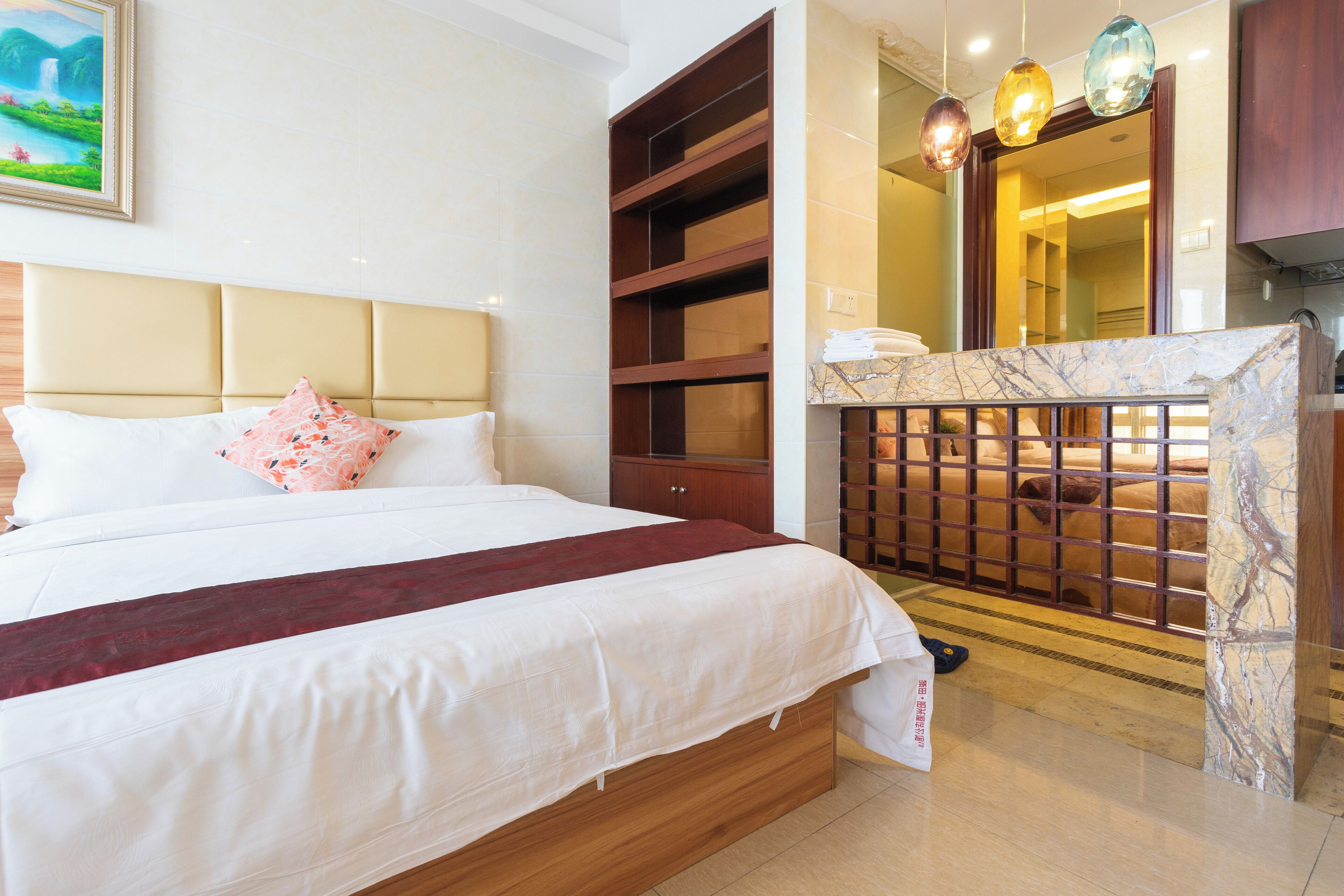 A hotel room with a large bed, wooden headboard, a marble accent wall, and a view of the bathroom.