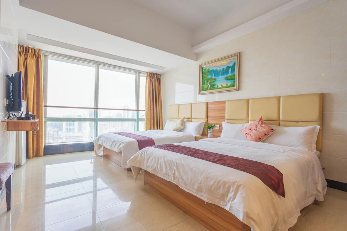A hotel room with two beds, a large window with curtains, a painting on the wall, and a television on the left.