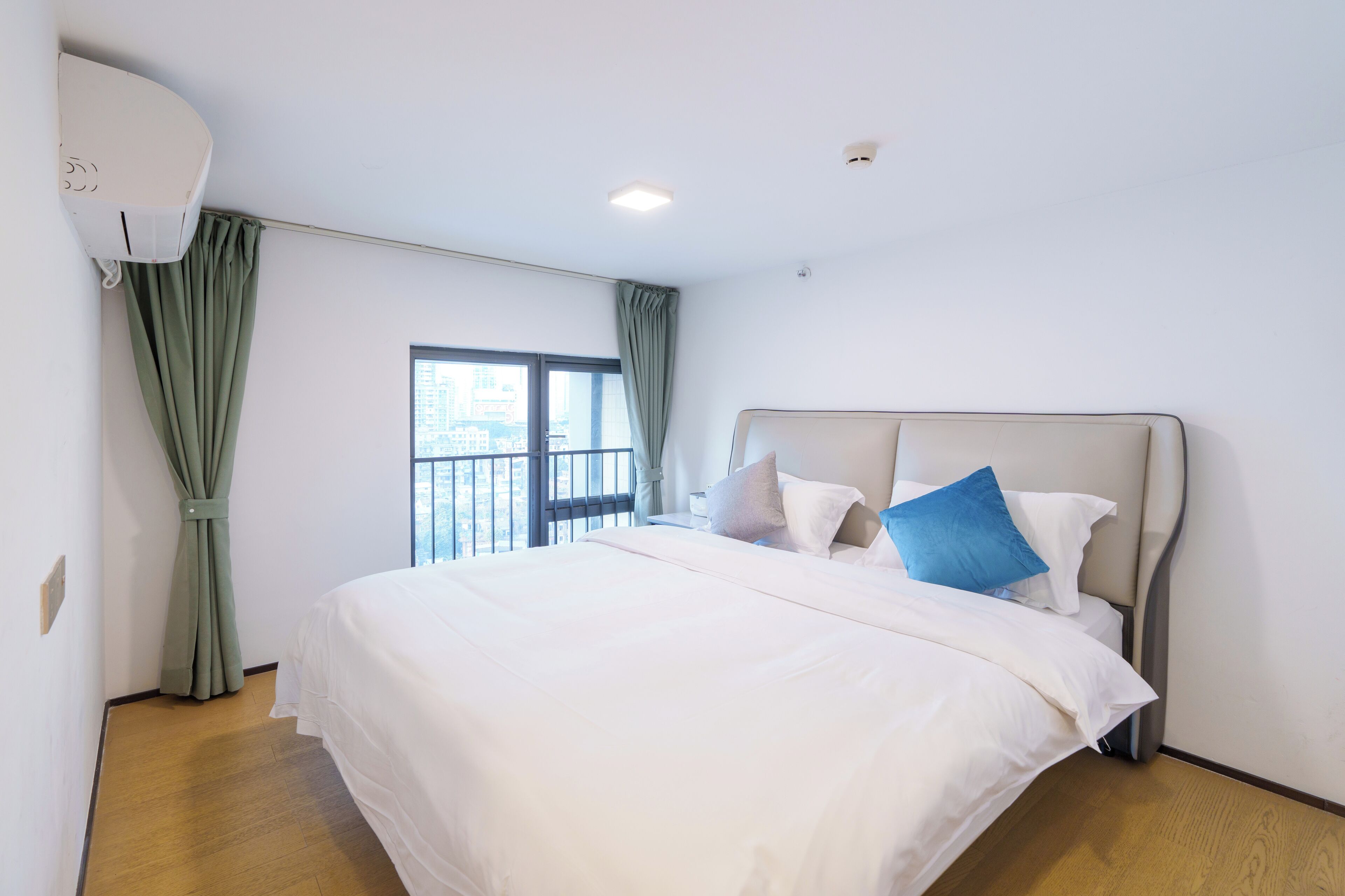 Une chambre d’hôtel avec un grand lit, une fenêtre avec des rideaux et un appareil de climatisation fixé au plafond.