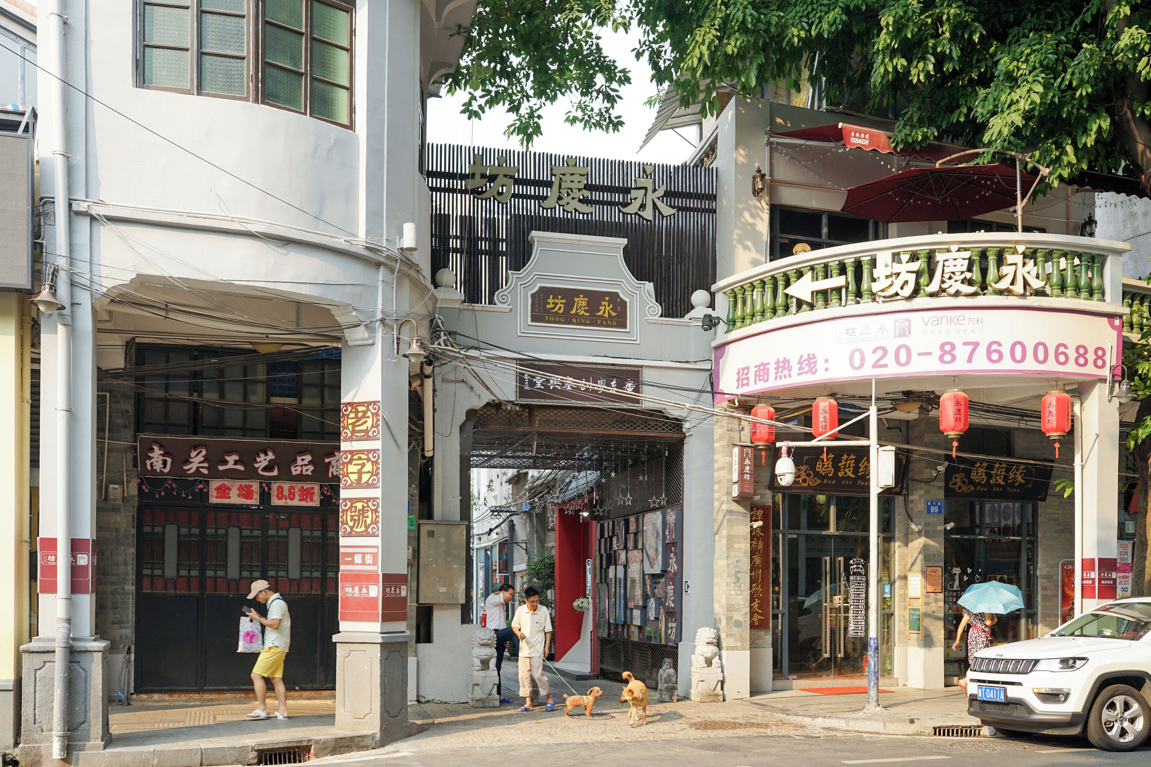 A street scene with a building entrance, a signboard, and a parked car.