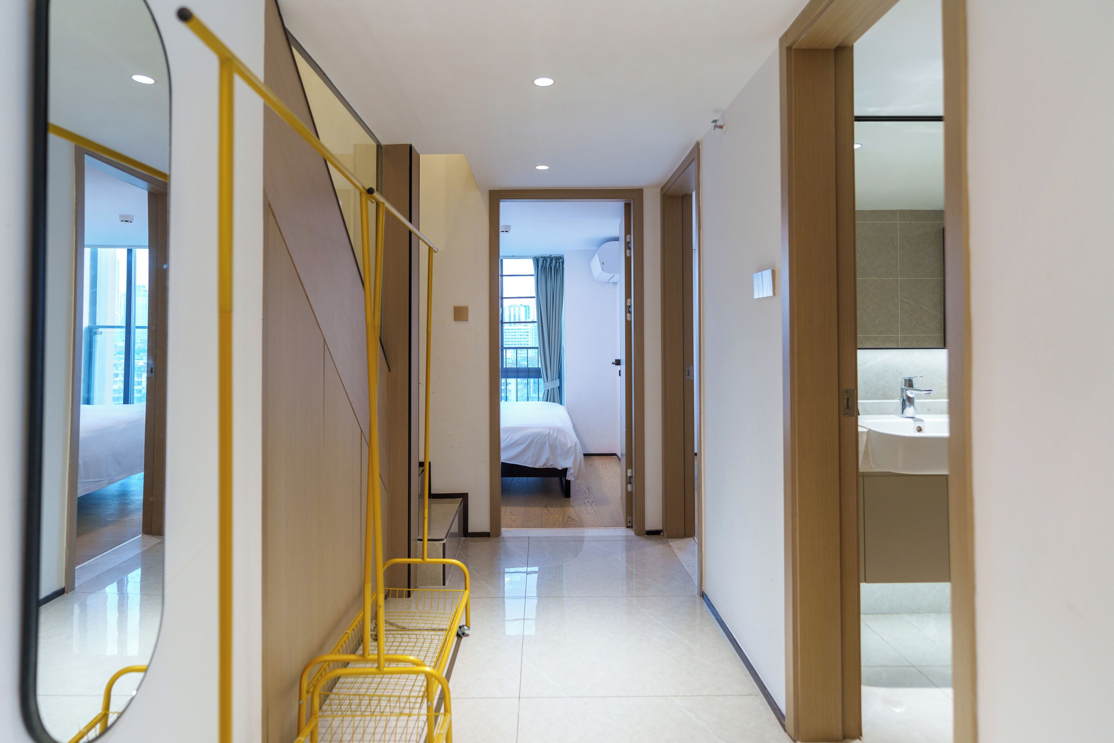Corredor de hotel com uma cama, um banheiro e um espelho.