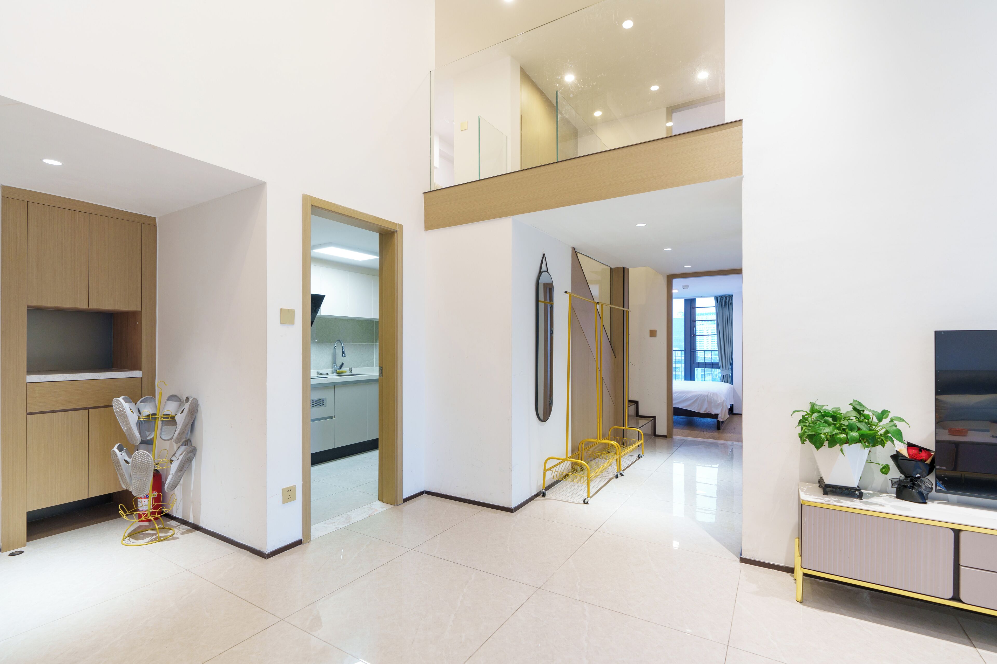 A modern hotel room with a kitchen area, a balcony, and a large window.