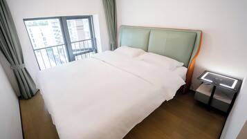 A neatly made bed with a wooden headboard, a bedside table with a lamp, and a window with curtains.