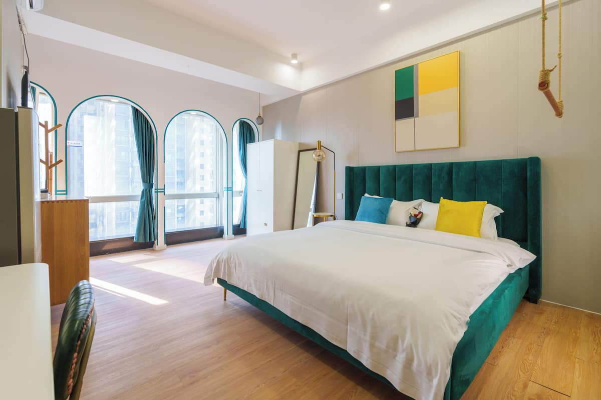 A modern bedroom with a large bed, a wardrobe, and a desk.
