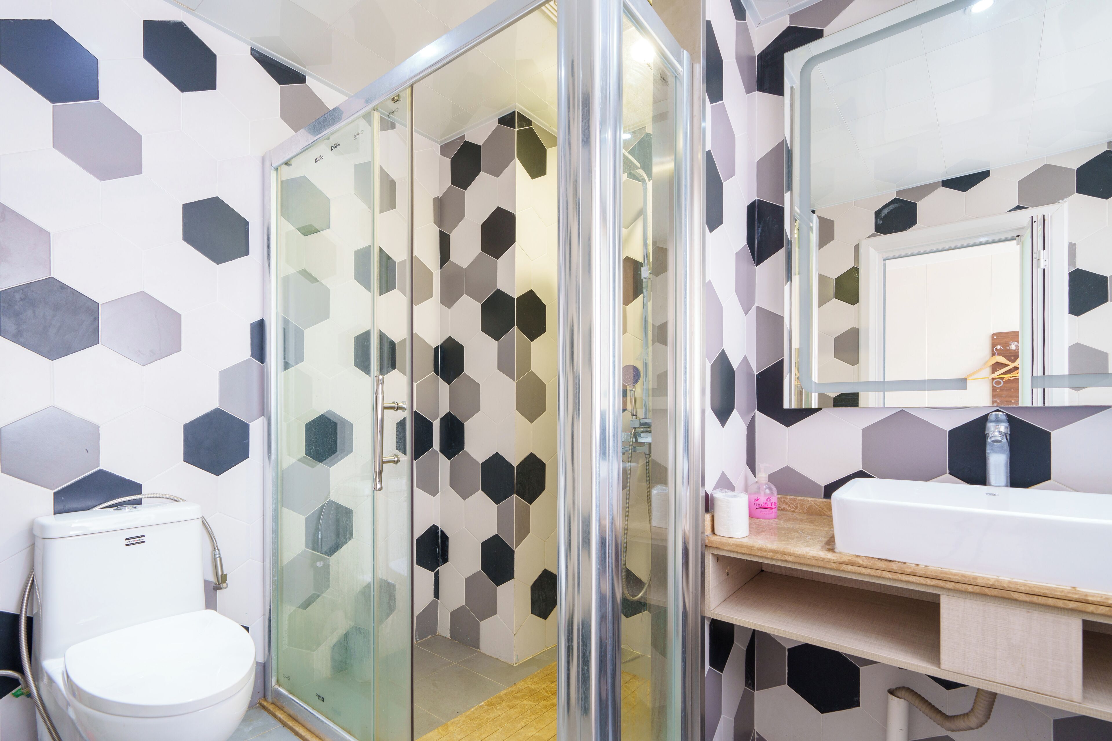 Un baño con cabina de ducha de vidrio, inodoro y lavabo con espejo.