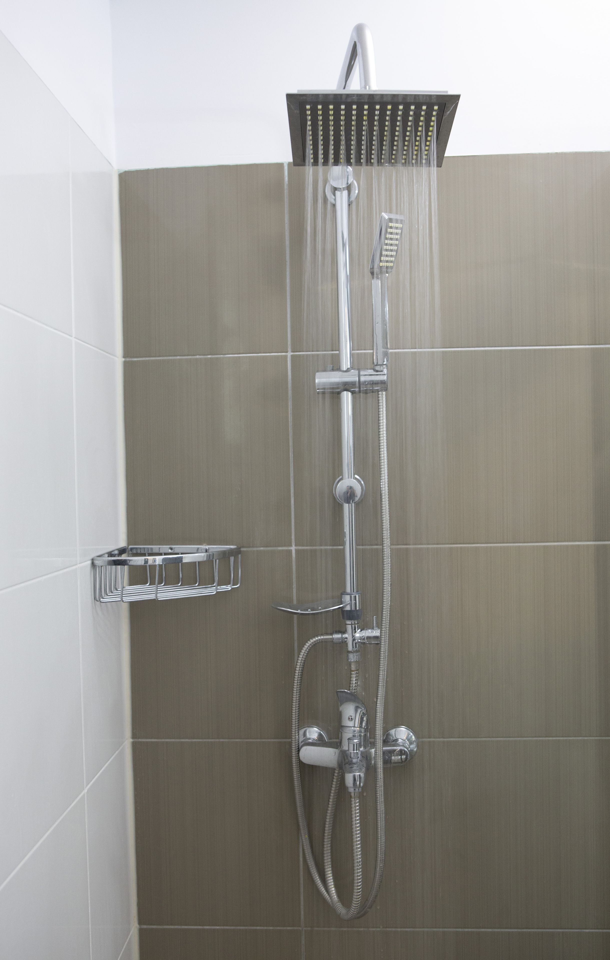 A shower with a handheld showerhead and a fixed showerhead, both mounted on a wall.