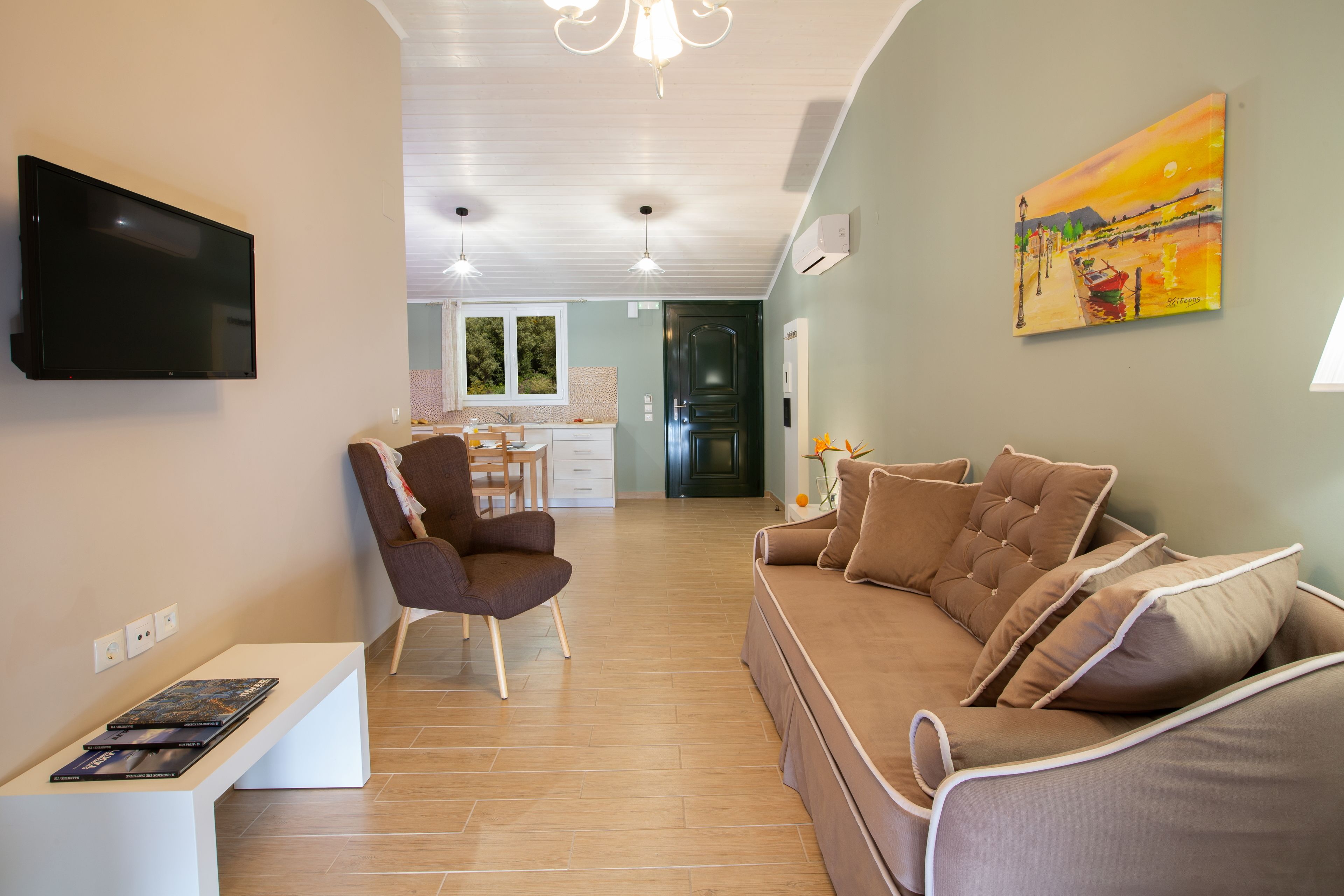 A modern living room with a flat-screen TV, a brown sofa, a chair, and a bench with books.
