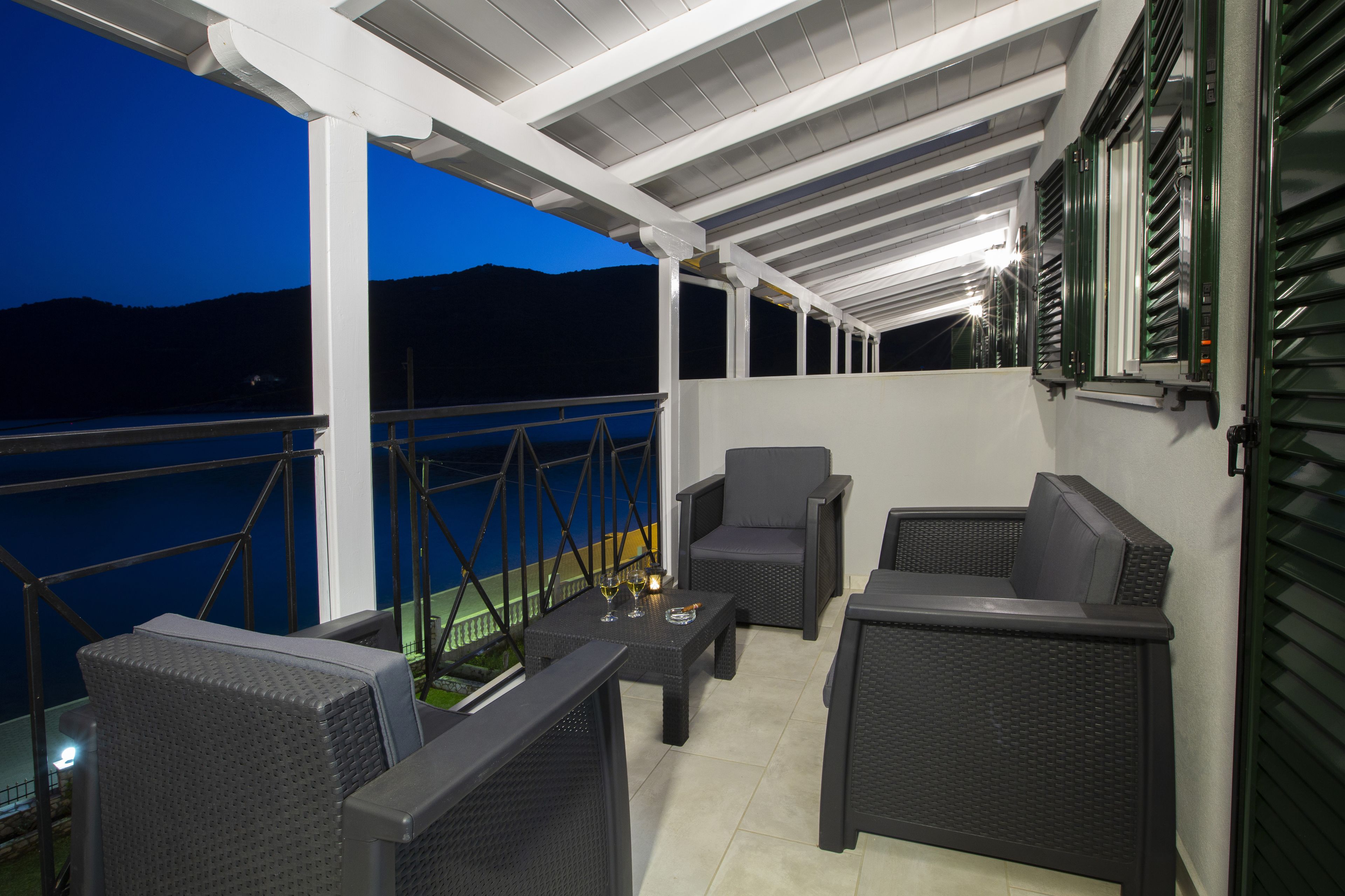 Un patio al aire libre con muebles de mimbre, una mesa con vasos y vista al agua.