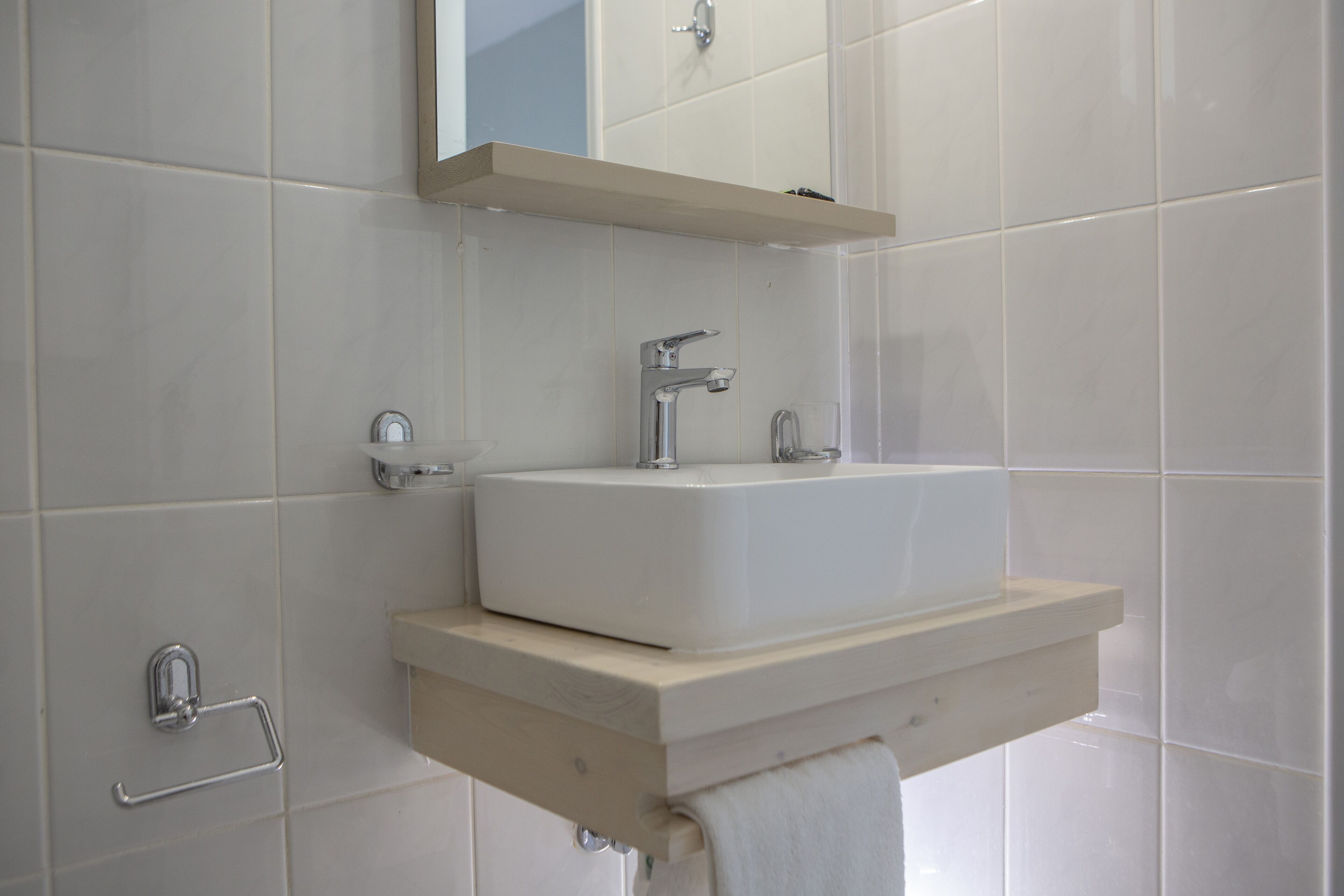 A bathroom with a white sink, a mirror above it, and a towel hanging on a rack.