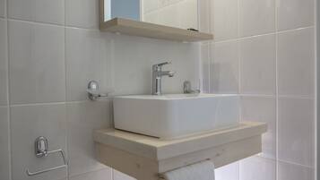 A bathroom with a white sink, a mirror above it, and a towel hanging on a rack.