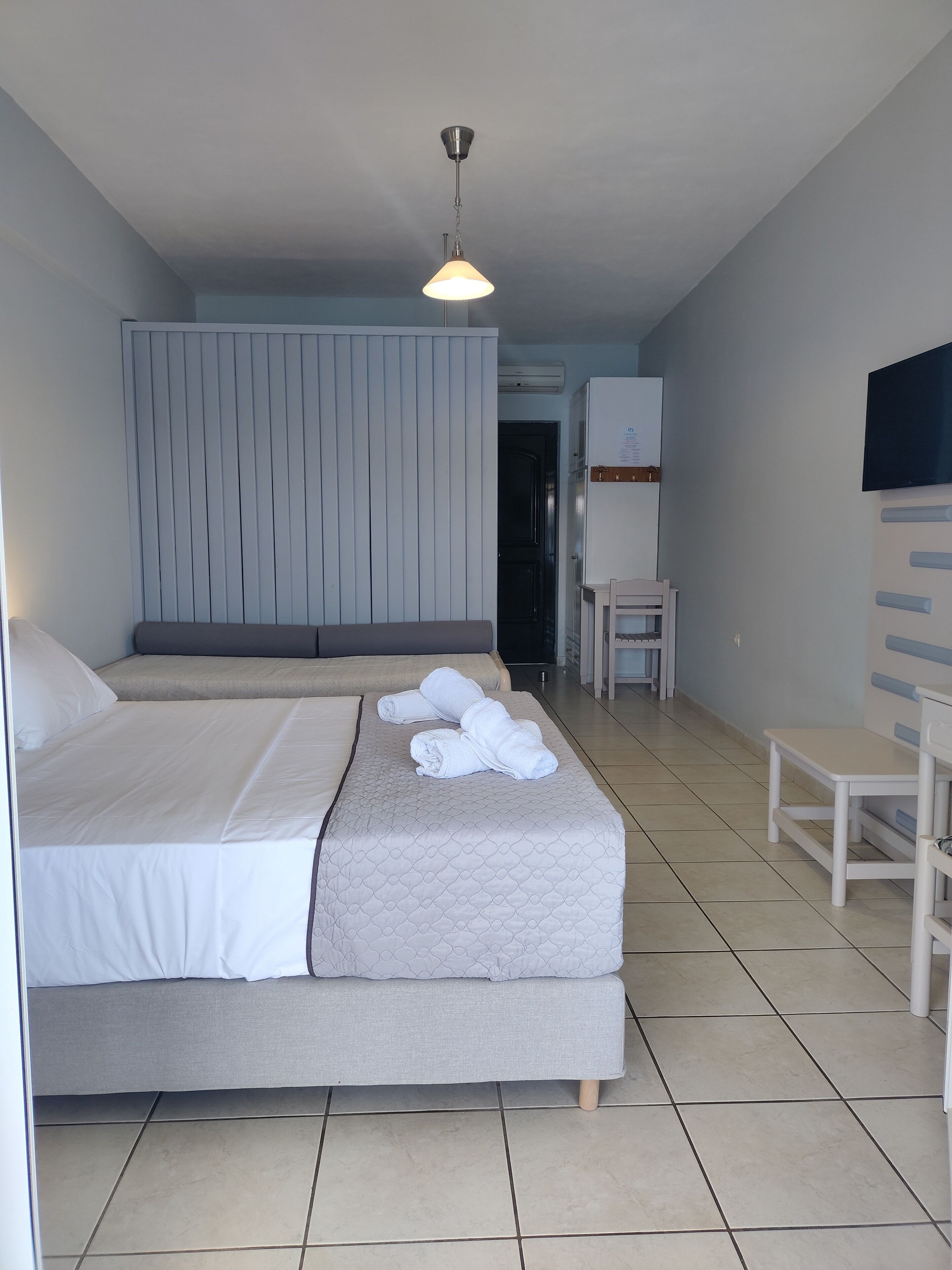 Habitación de hotel con cama, escritorio, silla y televisión en la pared.