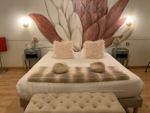 Un dormitorio ordenado con una cama grande, dos mesitas de noche, una alfombra mullida y un mural en la pared.