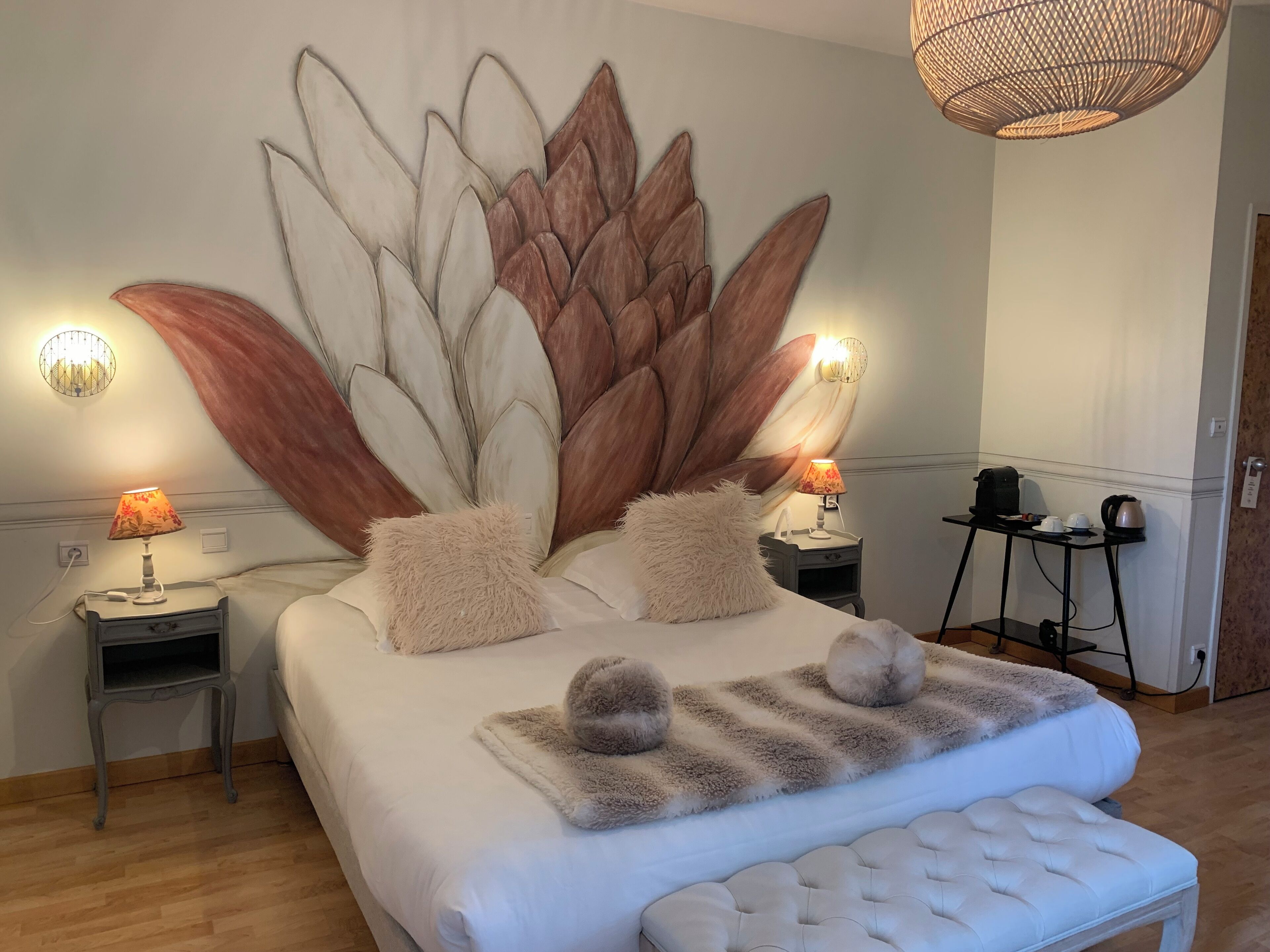 A bedroom with a large bed, two bedside tables with lamps, a small side table, a fluffy rug, and a wall-mounted light fixture.