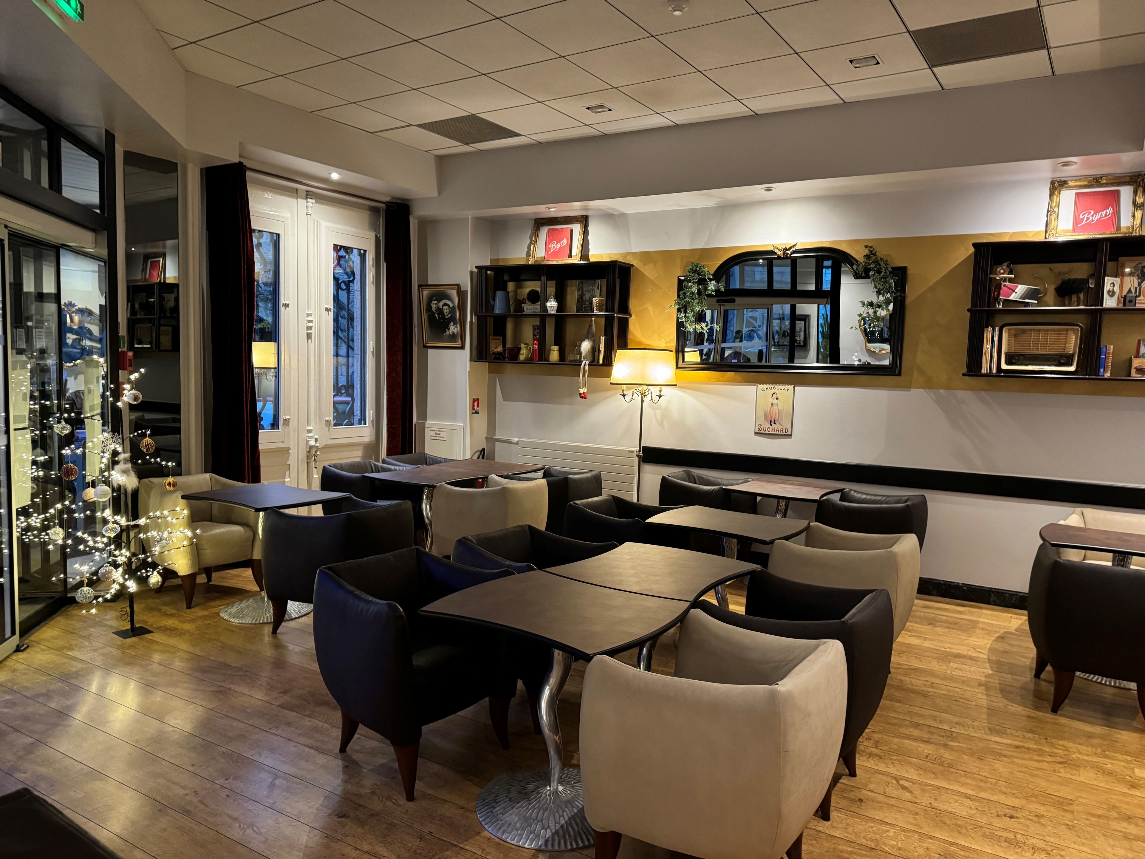 Un restaurante con una decoración moderna, que ofrece diferentes opciones de asientos como mesas y cabinas, un árbol de Navidad decorativo y varios adornos en las paredes.