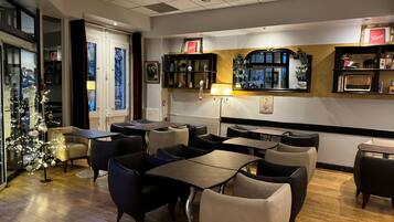 Un restaurante con una decoración moderna, que ofrece diferentes opciones de asientos como mesas y cabinas, un árbol de Navidad decorativo y varios adornos en las paredes.