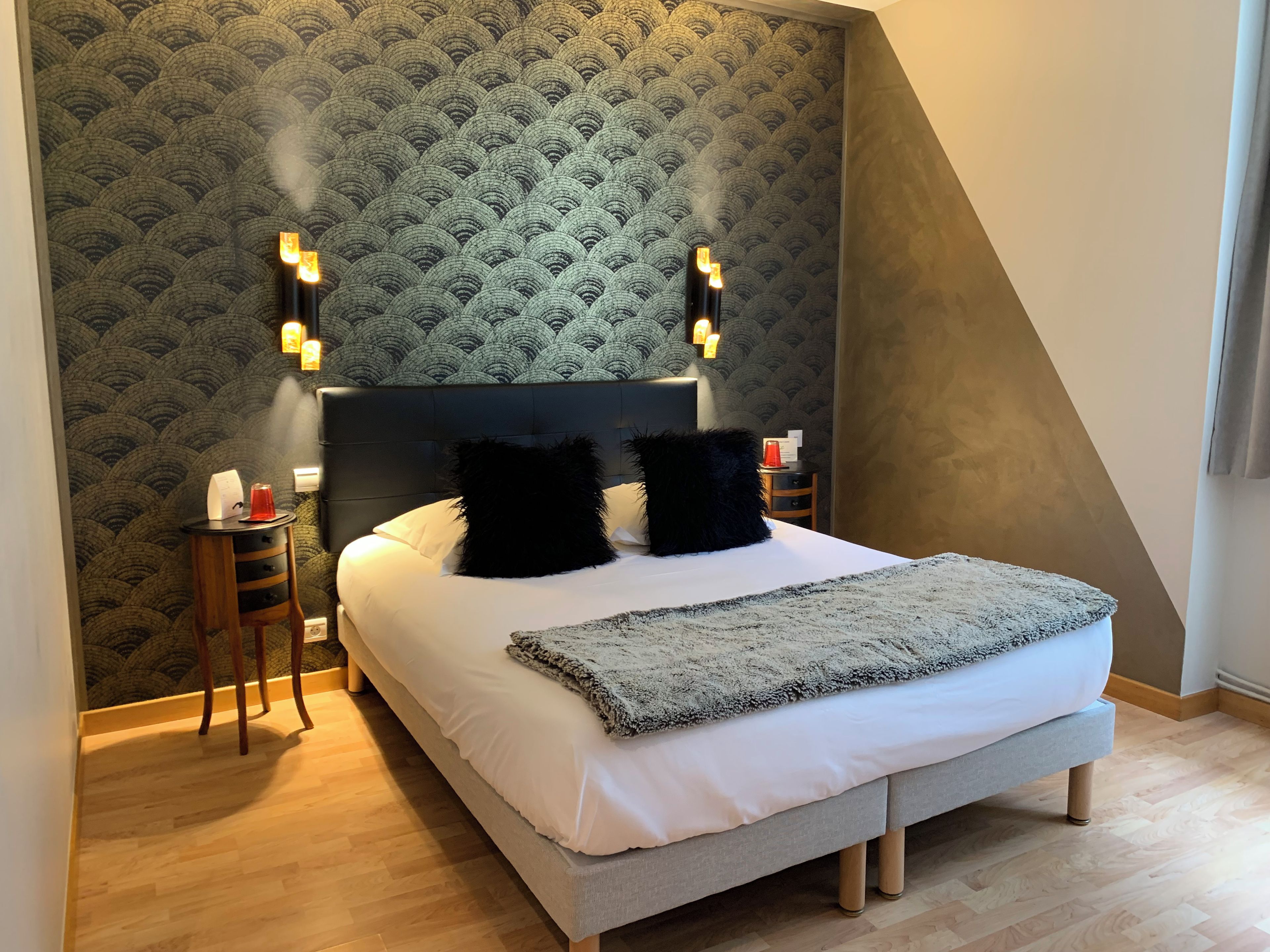 Un dormitorio moderno con una cama grande, dos mesitas de noche y un papel tapiz estampado.