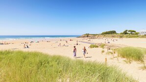 A beach with people walking, tents, and a grassy area in the foreground. - Hôtel Vintage (Quimperle)