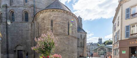 A historic stone building with arched windows and a dome, a flower planter in the foreground, and a clear sky.