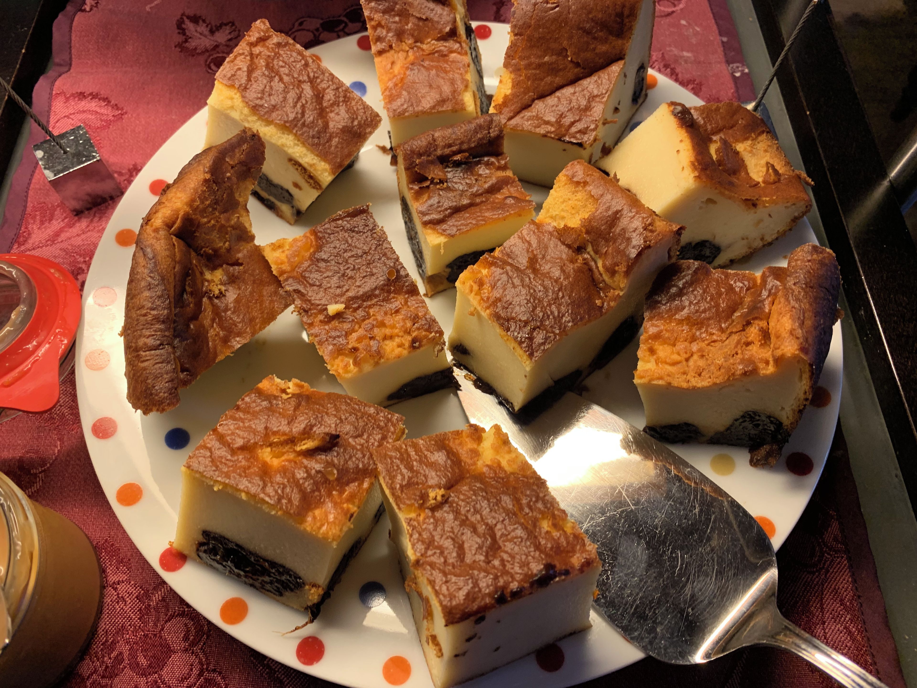 Une assiette remplie de petits desserts carrés à la croûte dorée, disposés sur une assiette blanche ornée de pois colorés.