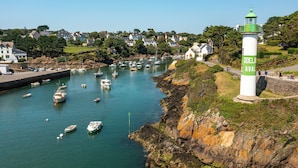A coastal town with a lighthouse, boats, and houses along the shore. - Hôtel Vintage (Quimperle)
