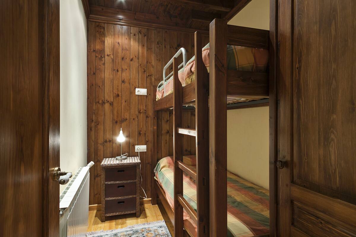 Ein Zimmer aus Holz mit Etagenbetten, einem Schminktisch und einer Lampe.