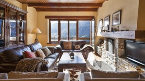 A cozy living room with a fireplace, leather sofa, and a stone fireplace surround.