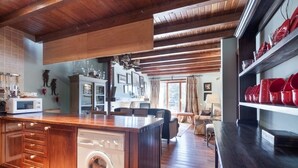 A kitchen with wooden cabinets, a built-in washing machine, and a dining area with a table and chairs.