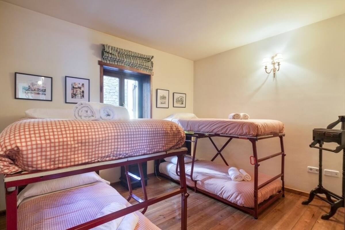 Ein Schlafsaalzimmer mit Etagenbetten, einem Fenster mit Ausblick und gerahmten Bildern an der Wand.