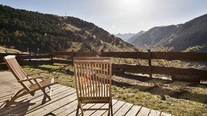 A wooden deck with two lounge chairs overlooking a mountainous landscape.