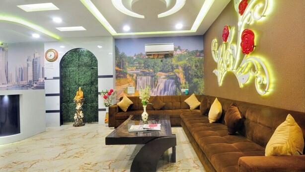 A modern hotel lobby with a brown sofa, a marble coffee table, and a mural of a waterfall. - Check In Room Main Bazar (New Delhi)