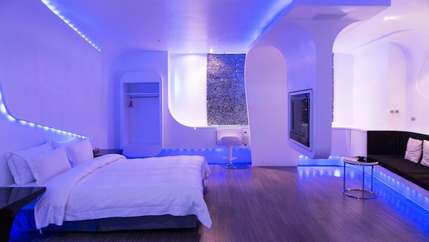 A modern bedroom with a bed, a small table, a TV, and a unique wall feature. - All-Ur Boutique Motel - Tai-Chung Branch (Taichung)