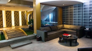 A modern living area with a sofa, coffee table, and a large window with a view of a waterfall. - All-Ur Boutique Motel - Tai-Chung Branch (Taichung)