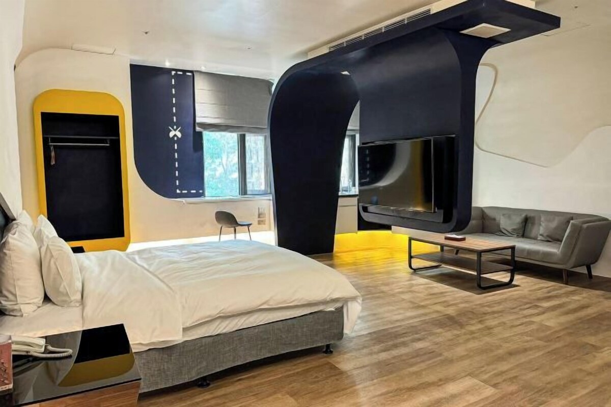Ein modernes Schlafzimmer mit Bett, Sofa und Fernseher.