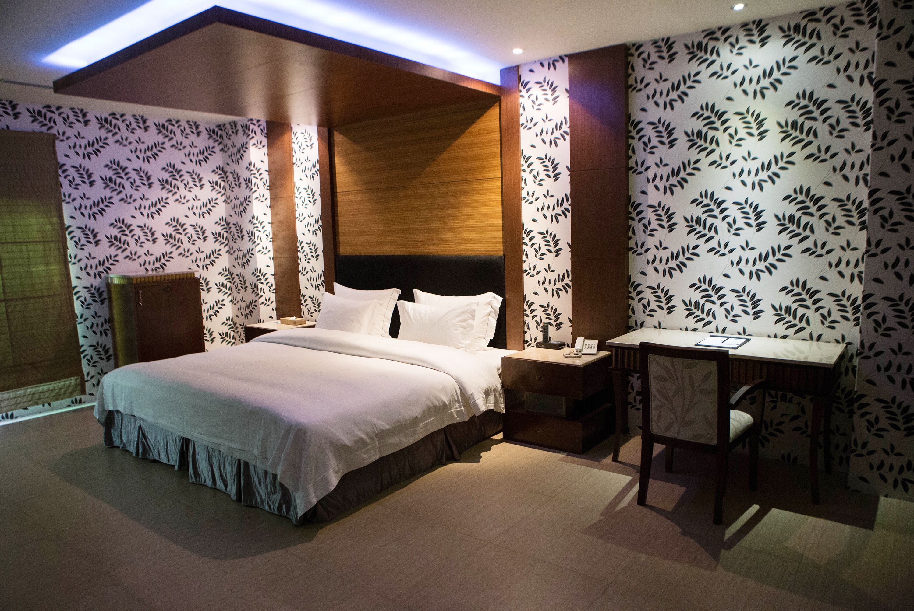 A modern hotel room with a large bed, a desk, and a chair.