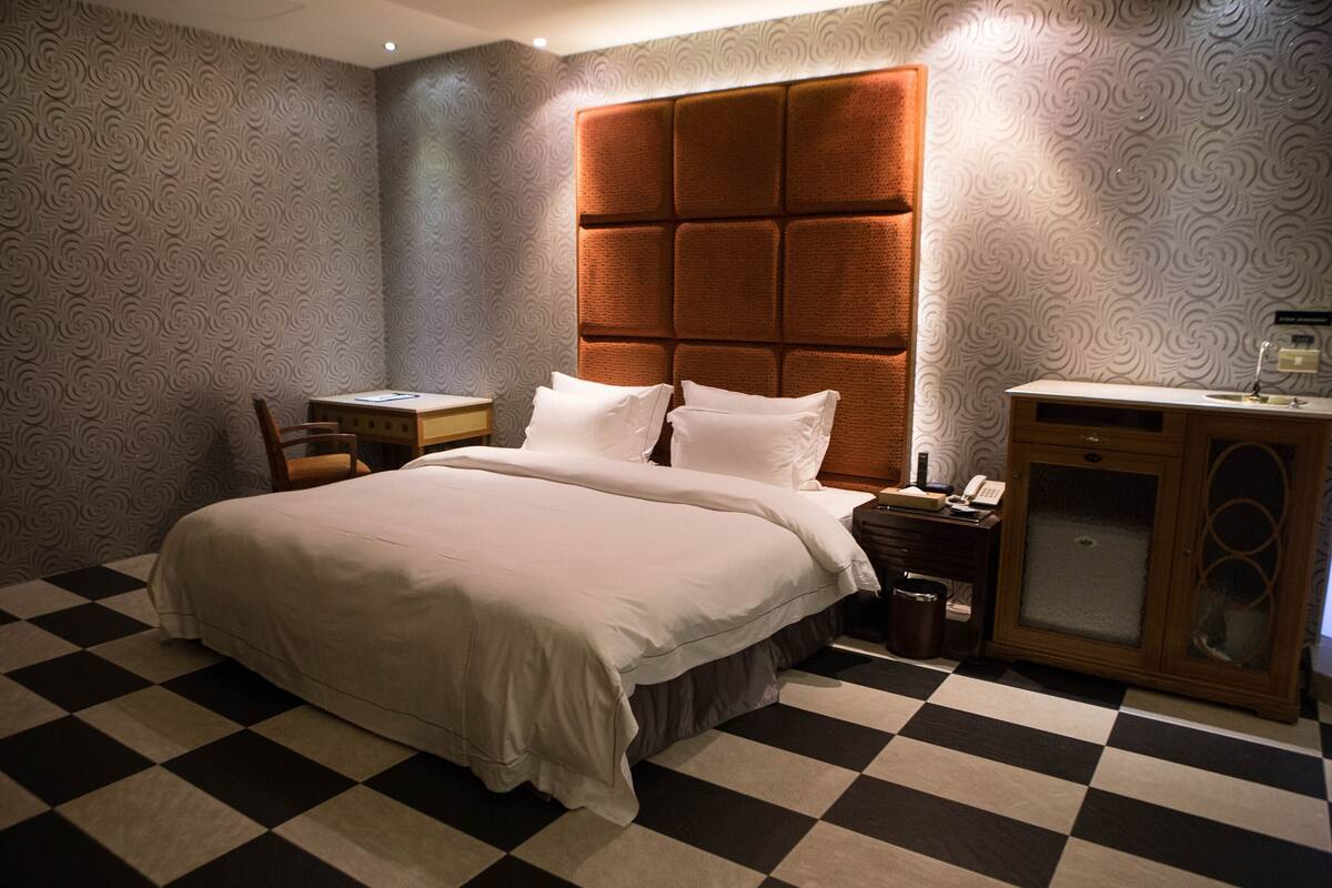 A hotel room with a large bed, a nightstand, a desk, and a cabinet.