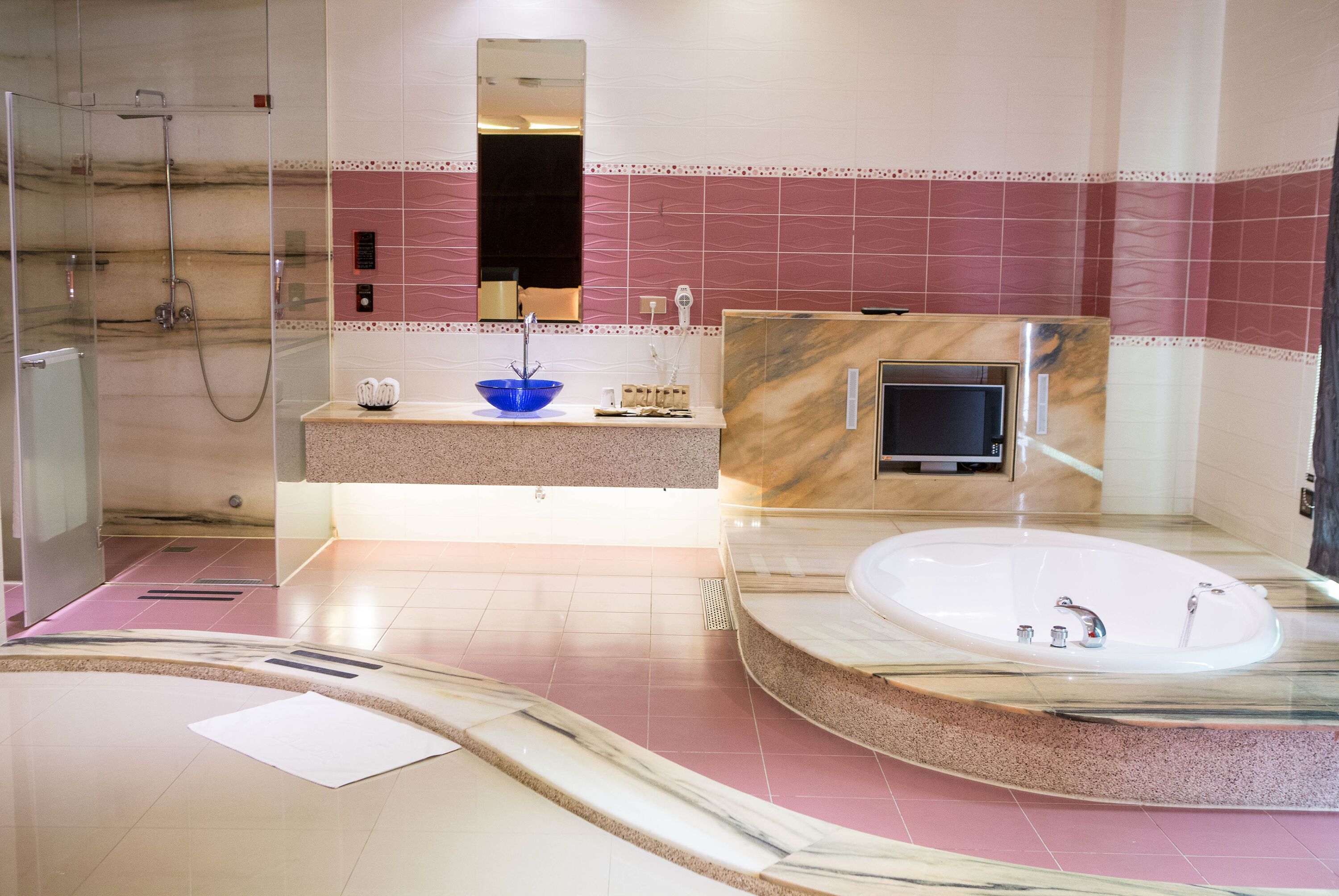 A modern bathroom with a glass-enclosed shower, a large marble sink, and a freestanding bathtub.