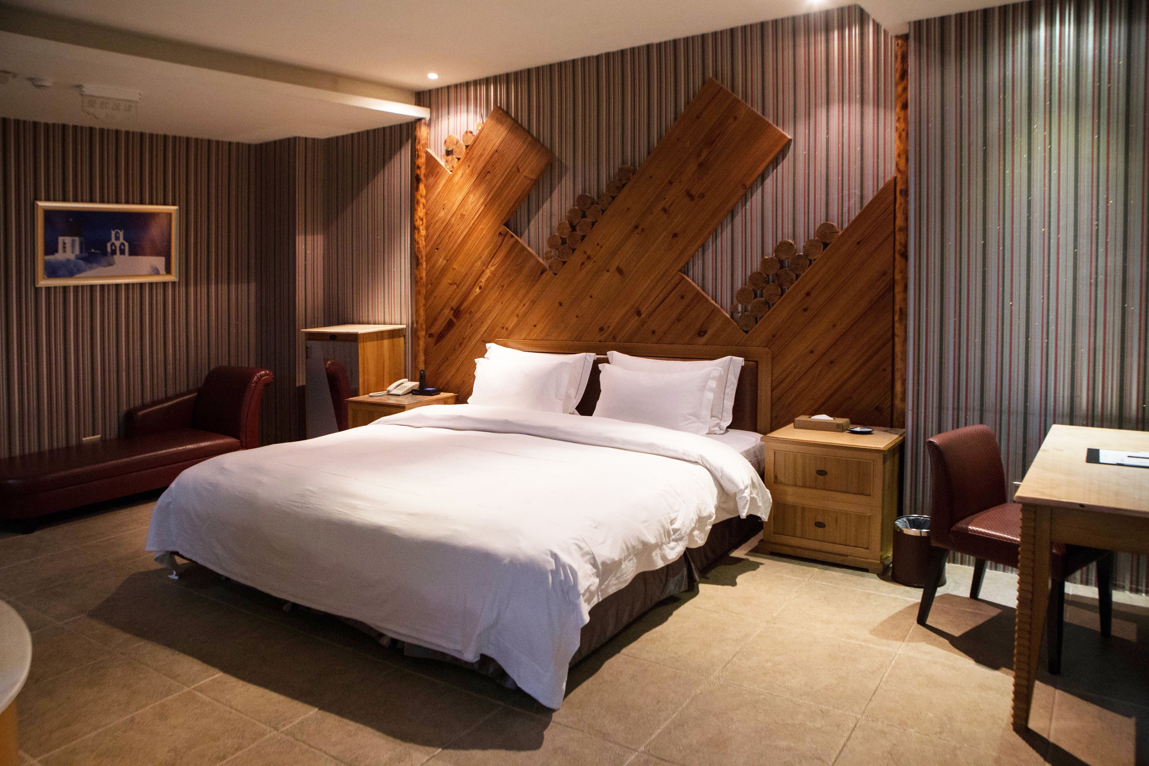 Habitación de hotel con una cama grande, un cabecero de madera, un escritorio y una silla.