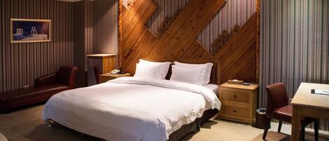 Habitación de hotel con una cama grande, un cabecero de madera, un escritorio y una silla.
