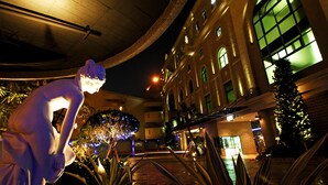 A nighttime view of a hotel courtyard with a statue, a Christmas tree, and a building with arched windows. - All-Ur Boutique Motel - Chang-Hua Branch (Changhua)