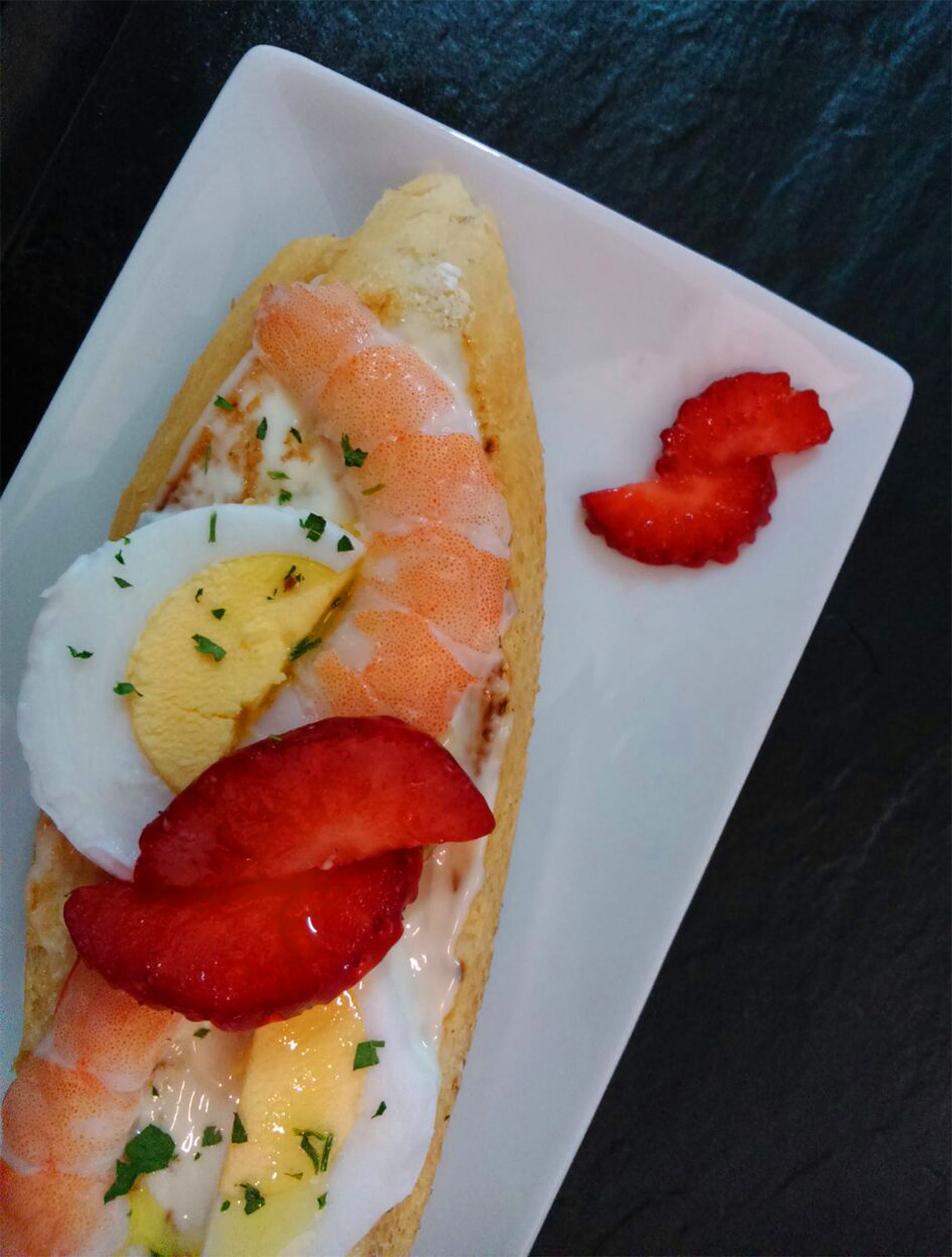 Un sandwich garni de divers ingrédients, servi sur une assiette blanche.