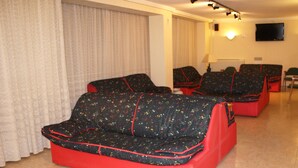 A hotel room with two red sofas with black patterned upholstery, a glass coffee table, and a television mounted on the wall. - Hotel Torres (Guijuelo)