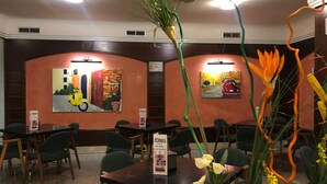 A restaurant with a modern interior, featuring green chairs, tables, and a menu stand. - Hotel Torres (Guijuelo)