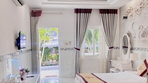 Quarto de hotel com duas camas, uma mesa, uma cadeira e vista para o exterior.