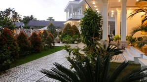 Um jardim bem cuidado com um caminho pavimentado que leva a um edifício com varanda.