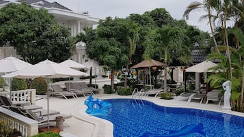 Una piscina al aire libre, sombrillas, sillones reclinables de piscina