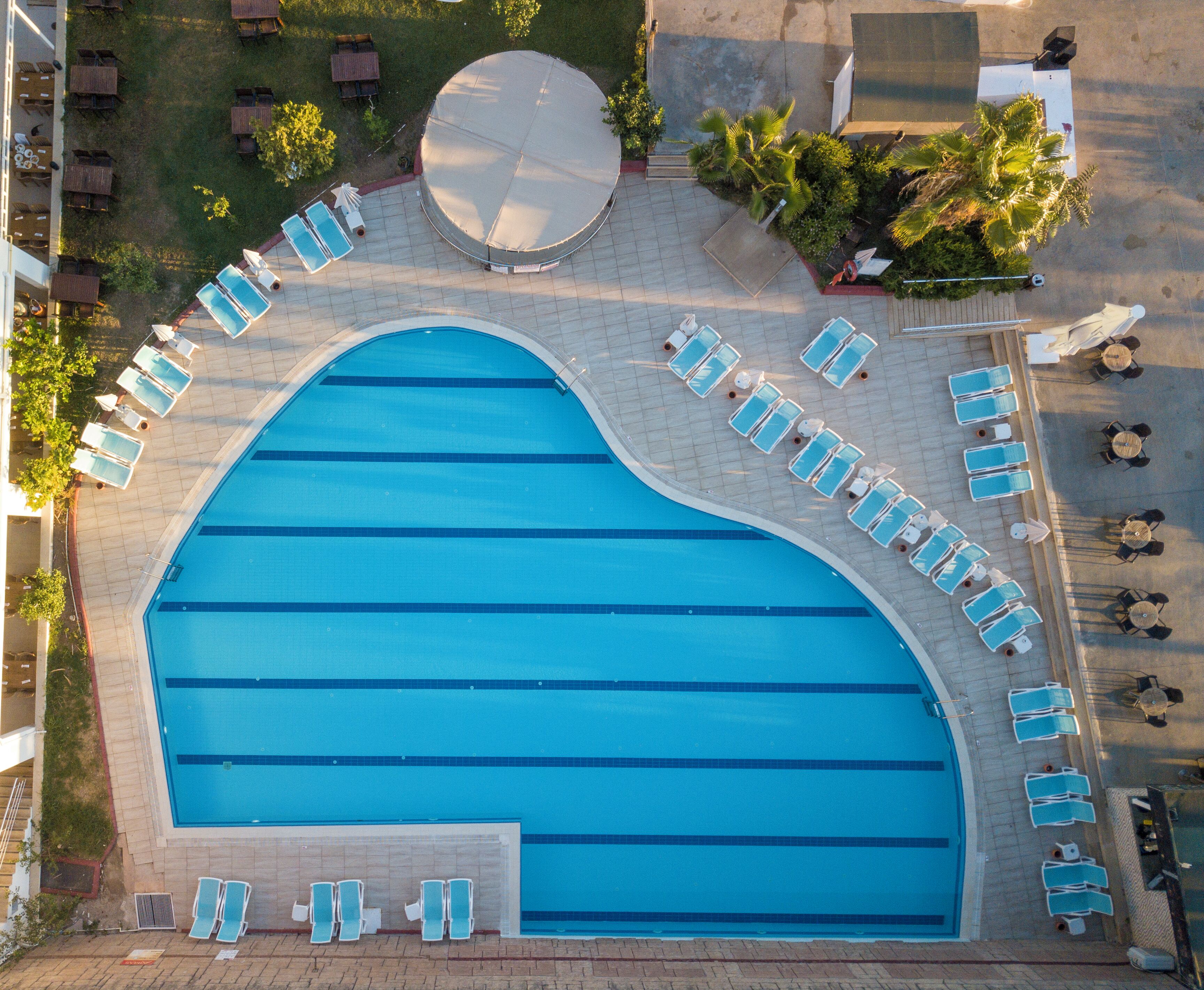 An aerial view of a swimming pool with multiple sun loungers and a circular seating area.